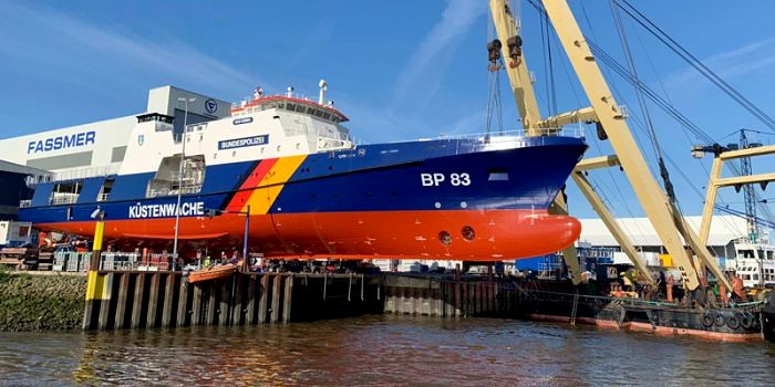 Küstenwachboot mit rot konservierter Unterwasserzone am Werftkran