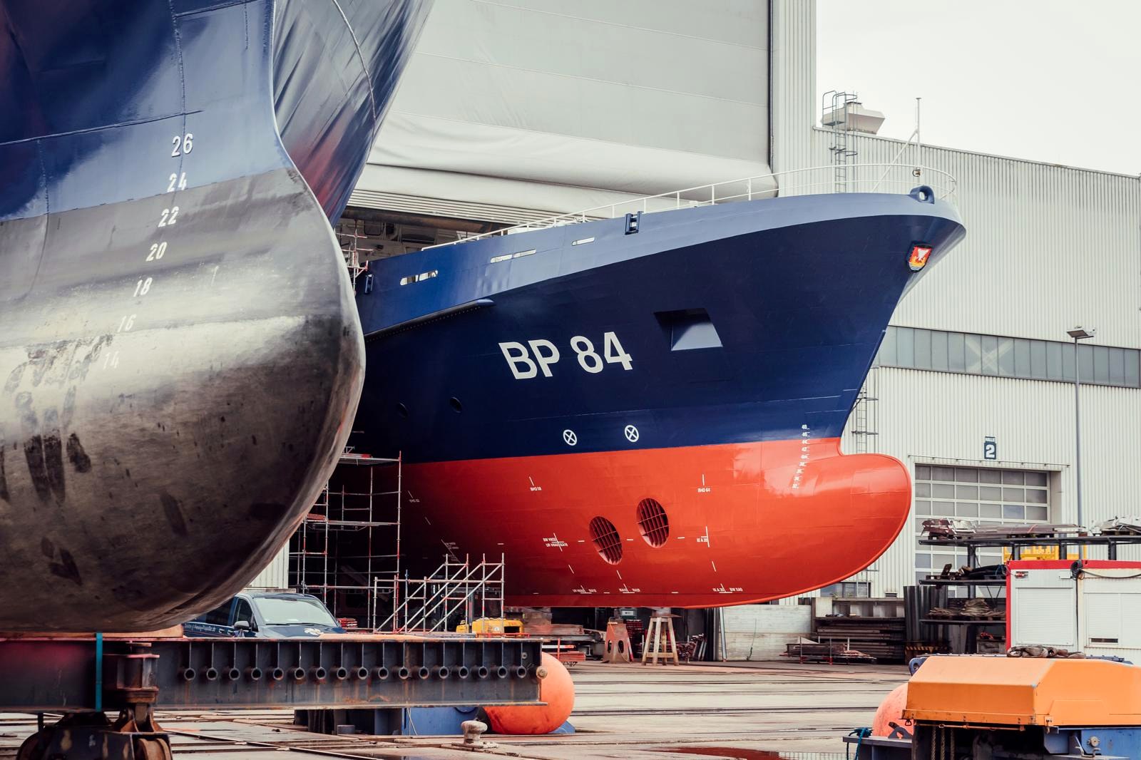 Bug des Neubaus BP 84 mit blauer Rumpf- und roter Unterwasserbeschichtung vor der Baudockhalle