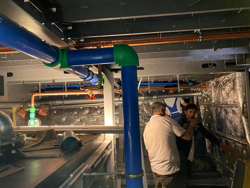 Isolierer arbeiten an einer Rohrleitungsdurchführung im isolierten Maschinenbereich
