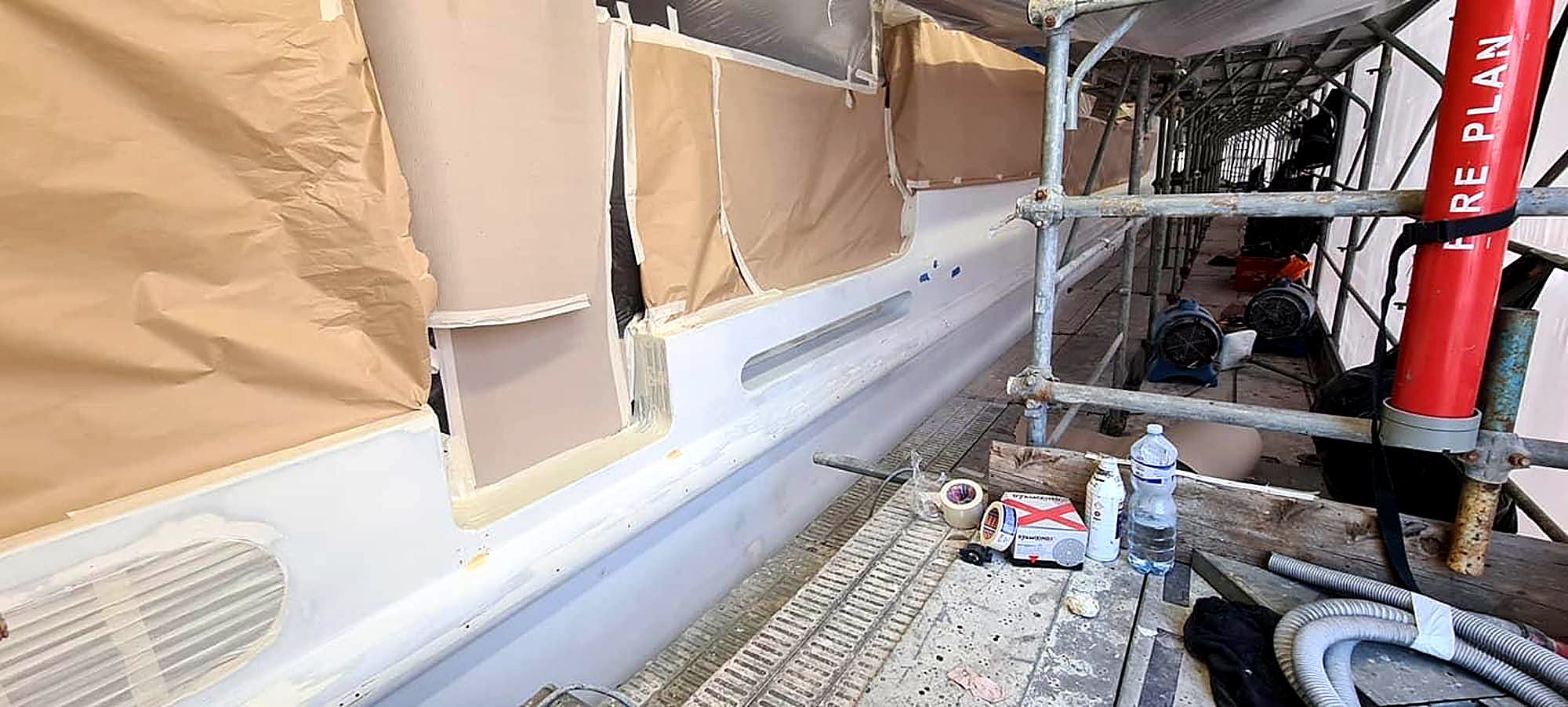 Abdeckarbeiten und Scheuerleiste am Yachtrumpf während des Refits
