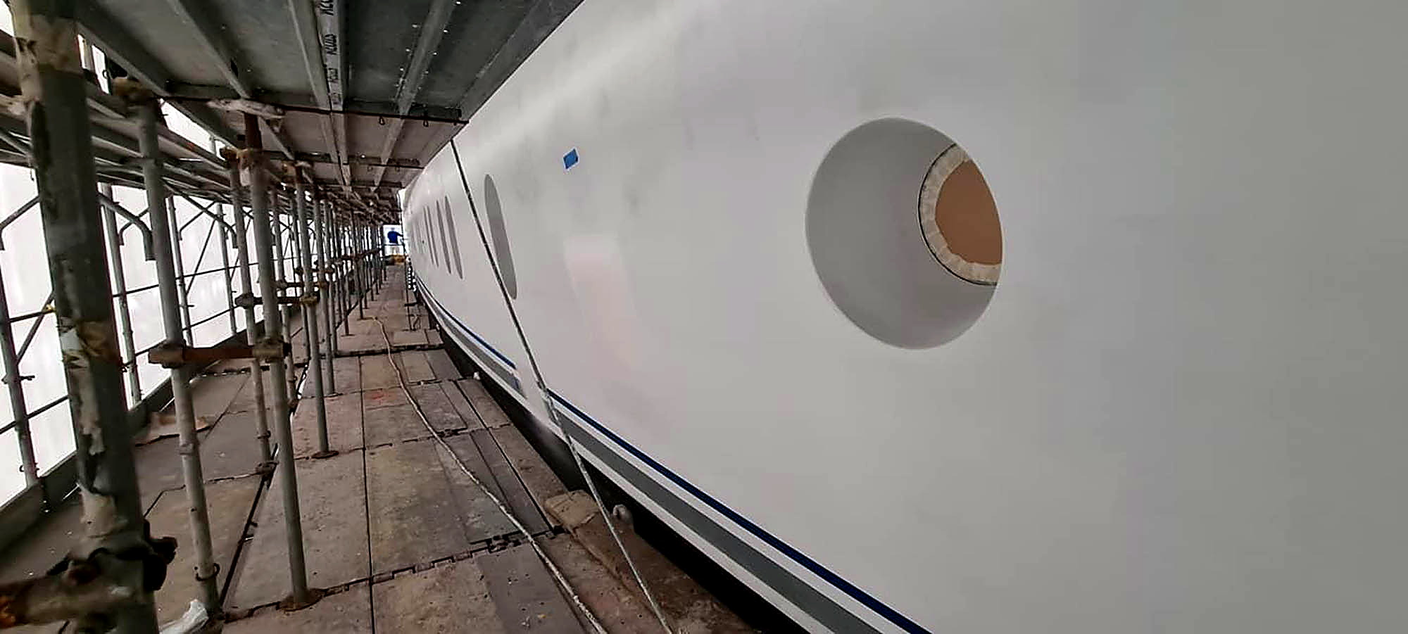 Yachtrumpf im Refit-Gerüst mit fertig beschichteter Bordwand