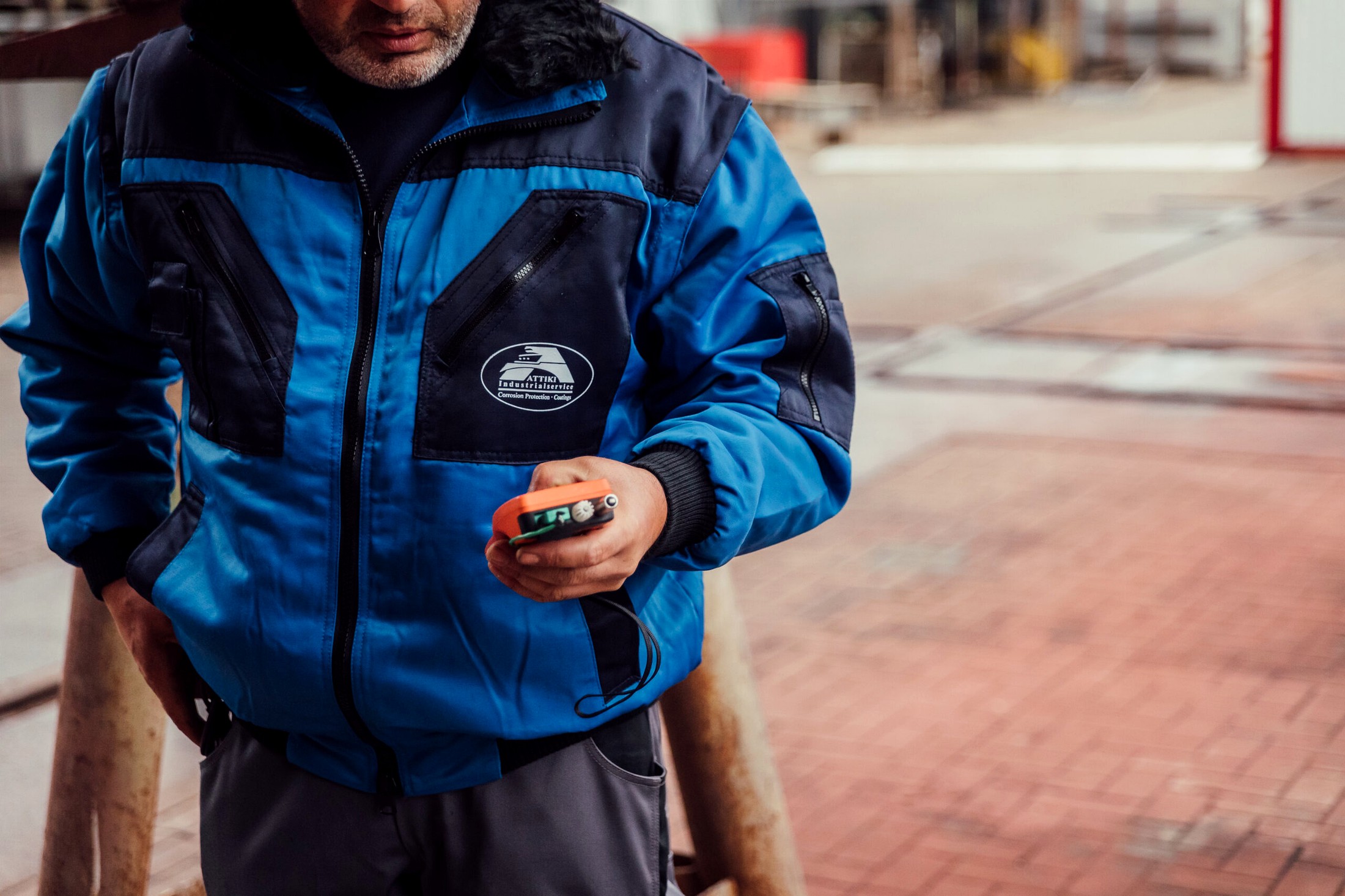 ATTIKI-Mitarbeiter mit Schichtdickenmessgerät auf dem Werftgelände